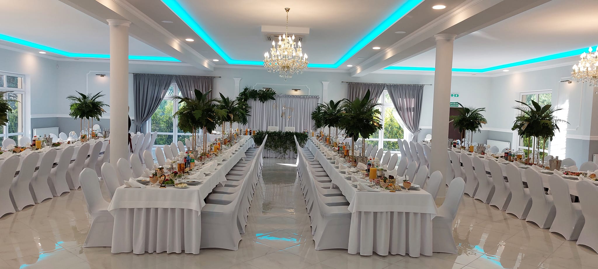 Sala Bankietowa Glamour Mazowsze - sala główna z podświetleniem LED turkusowym, długie stoły białe z dekoracją palmową