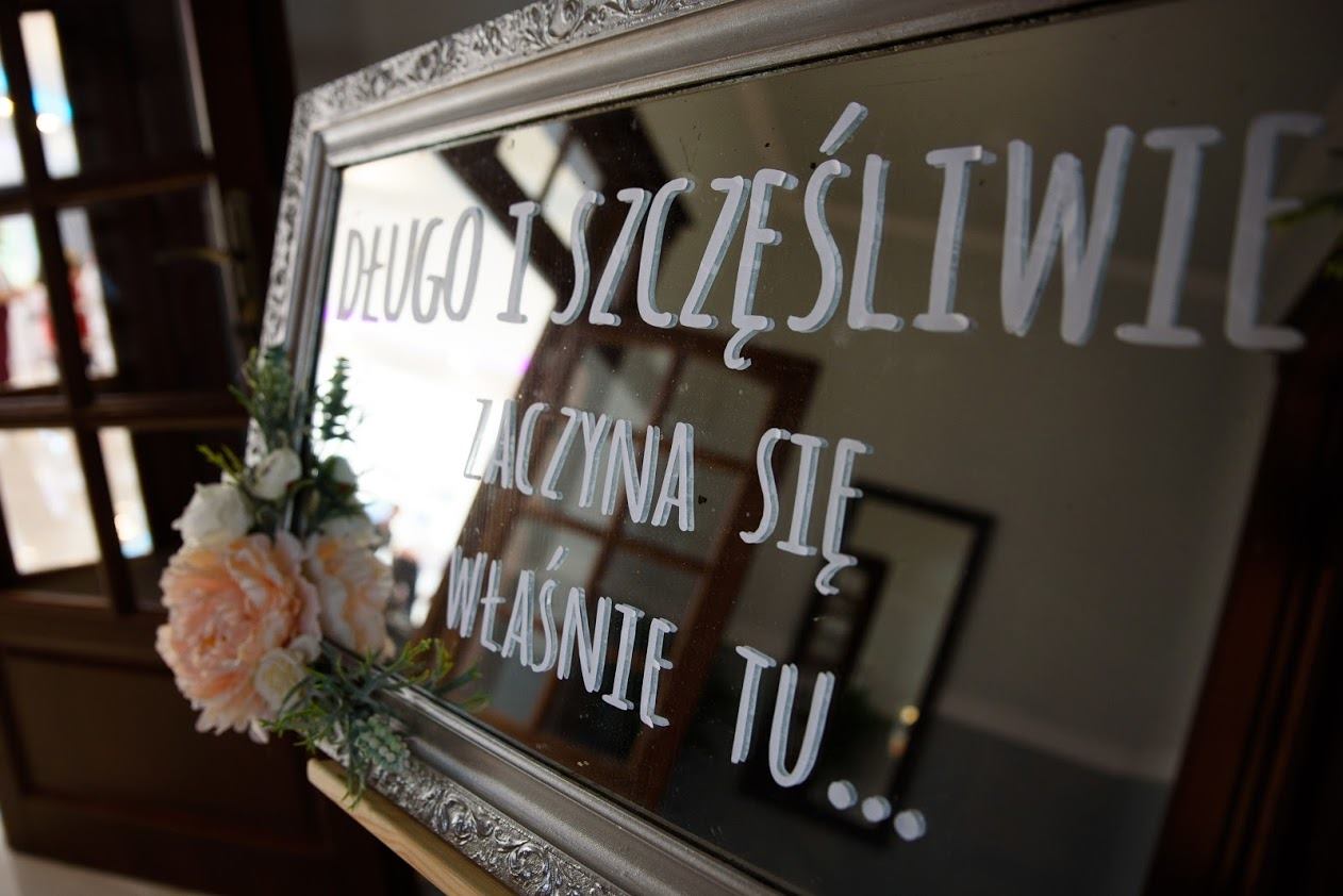 Sala Weselna Glamour Chroboty - lustro powitalne z napisem 'Długo i szczęśliwie zaczyna się właśnie tu' i bukietem róż