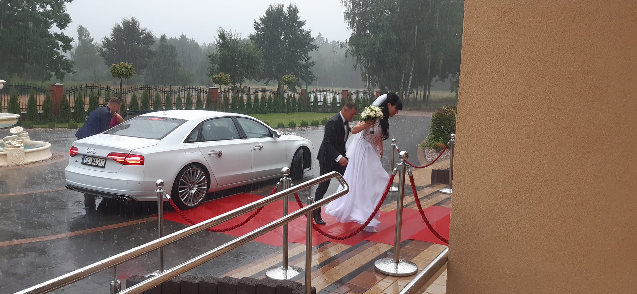 Sala Weselna Glamour Chroboty pod Żyrardowem - przyjazd pary młodej w deszczu, czerwony dywan i Audi A8 przed wejściem do sali