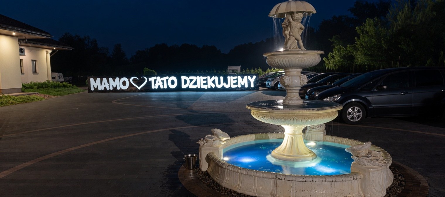 Sala Glamour Mazowsze - fontanna na placu przed salą wieczorem ze świetlnym napisem 'Mamo Tato Dziękujemy', podziękowanie pary młodej dla rodziców